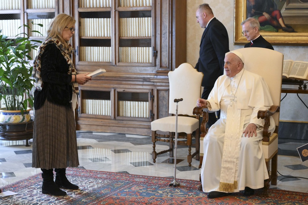 Church needs theologians who grapple with modern world, pope says Pope Francis, seated, smiles while listening to Maeve Heaney speak.