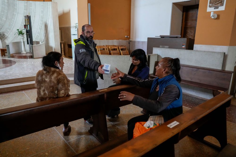 Fr. Andrea Conocchia, second from left, distributes personal hygiene items to transgender women as they sit in the Beata Vergine Immacolata parish church in Torvaianica, Italy, Nov. 16. Pope Francis has built an ongoing relationship of welcome with a community of trans women in Torvaianica.