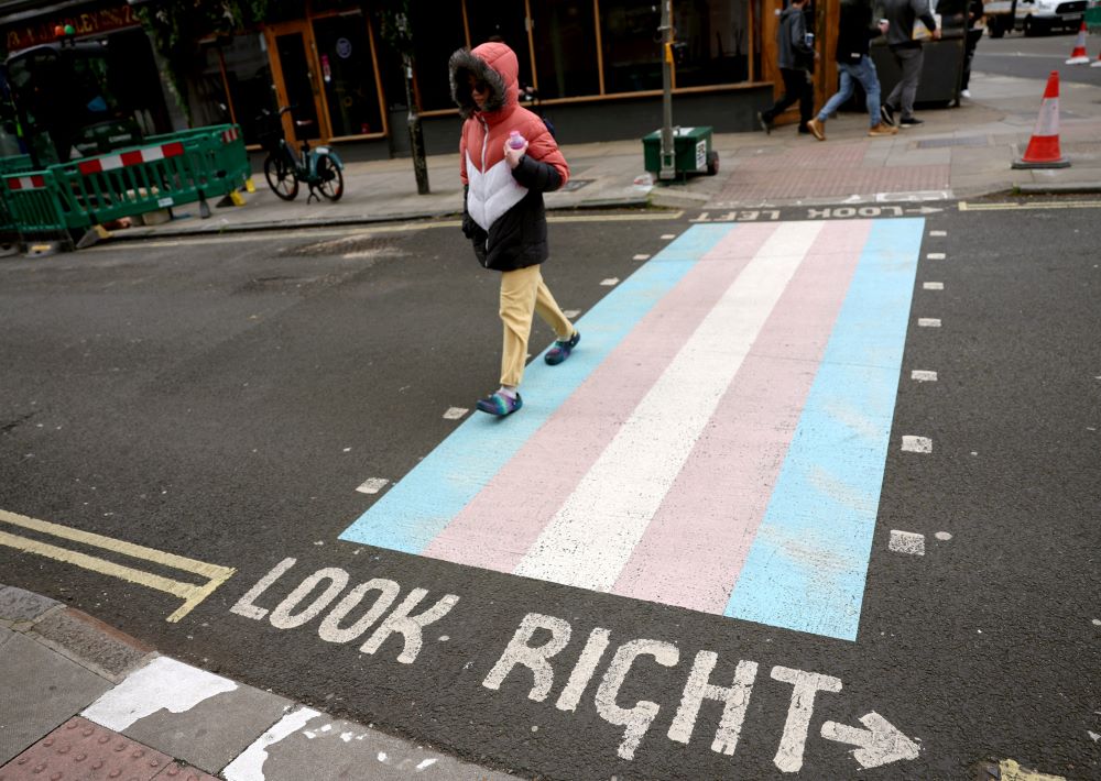A person walks on a pedestrian crossing decorated with the pattern of the transgender flag on a street in London April 10.