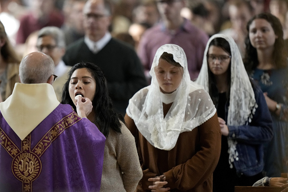 People receive communion during Catholic Mass at Benedictine College Dec. 3, 2023, in Atchison, Kansas. Many students, many of whom grew up in conservative Catholic families, jokingly call it “the Benedictine bubble.” And it might be a window into the future of the Catholic Church in America. (AP/Charlie Riedel)