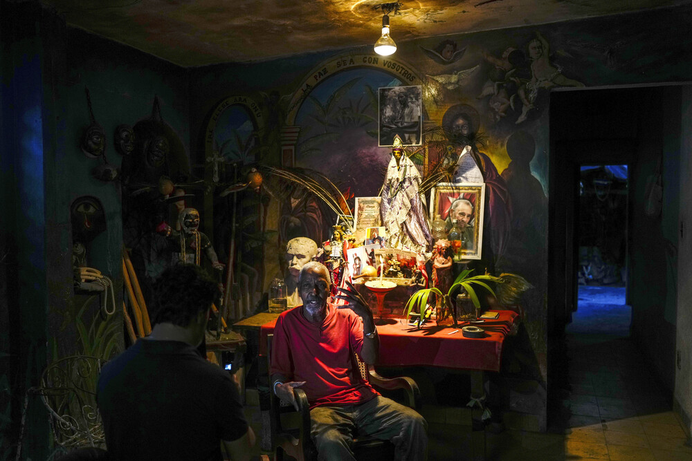 Religious diversity in Cuba Man sits in front of altar in dim room