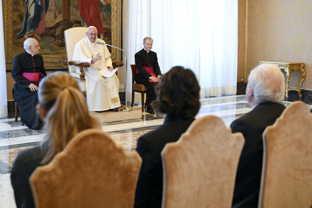 Pope Francis, Centesimus Annus Foundation, sustainable finance. Pope Francis seated, flanked by Cardinals, people sit facing him, the back of their heads to the camera.
