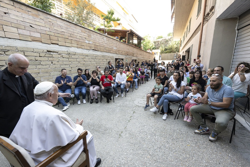 Pope Francis School of Prayer Pope Francis, seated, pictured from behind facing apartment residents in brick courtyard
