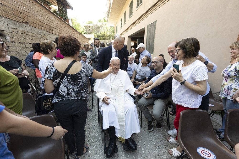 Pope Francis visits Roman neighborhood Pope Francis, in a wheelchair, is caressed by devotees.