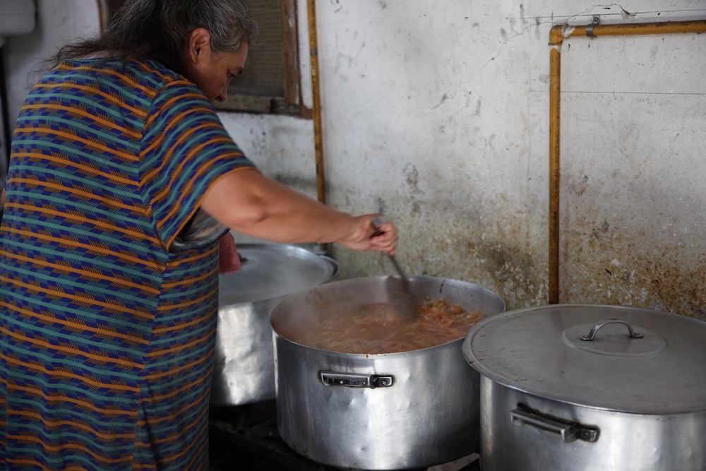 Argentina's poor want Pope Francis back Woman bends over stove stirring food in large aluminum pots