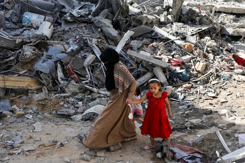 Pope renews call for ceasefire after hostage release Woman and child step gingerly though rubble