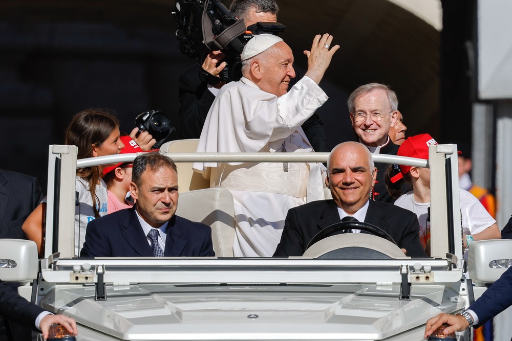 Pope Francis audience Pope Francis, standing in popemobile and framed by driver and attendants, waves to crowds