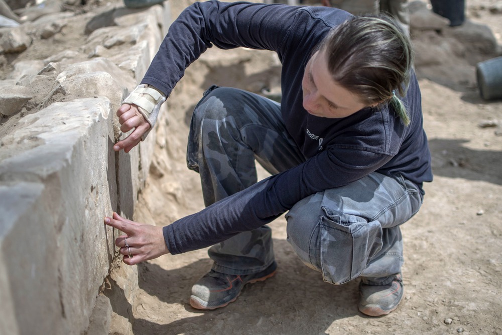 Israel Church painting discovery Archaeologist kneels down to examine stone structure