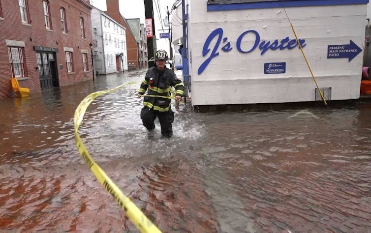 Sea levels, temperatures, and coastal economies First responder wades through knee-deep water in street