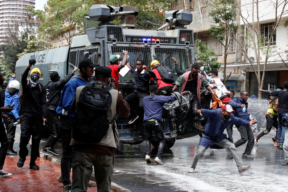 Kenya Student protests over Finance Bill, Nairobi 2024. People jump in front of and on large, armored vehicle in street.