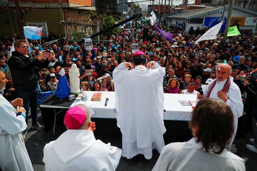 Buenos Aires Mass Altar pictured from behind, foregrounded are vested clergy, and frame fills with assembled laity
