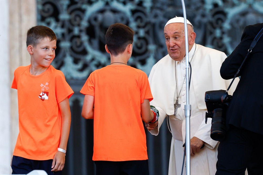 Pope Francis greets altar servers, Rome, 2024. Pope Francis, standing, bends to shake the hand of a young altar server.