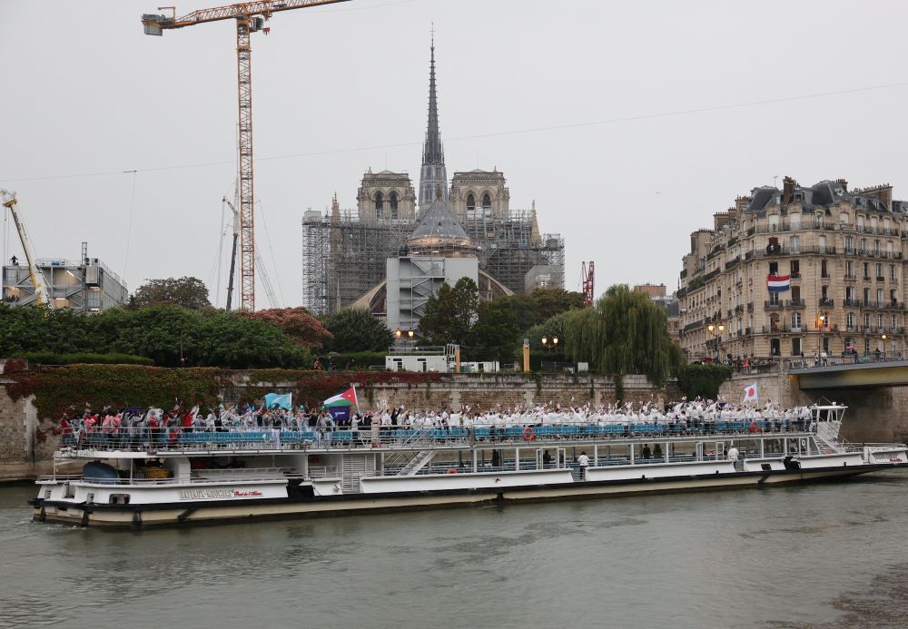 An athlete boat on the Seine River passes in front of the Notre Dame Cathedral July 26, 2024, during the opening ceremony of the Olympic Games in Paris. An athlete boat on the Seine River passes in front of the Notre Dame Cathedral July 26, 2024, during the opening ceremony of the Olympic Games in Paris.