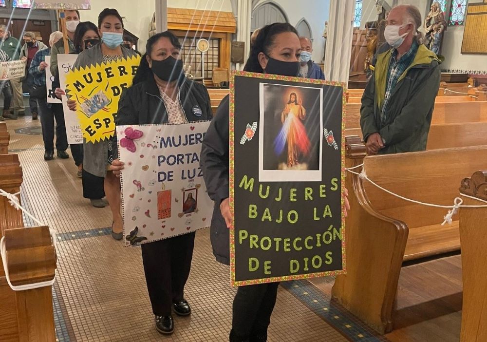 Members of women's support circles gather at Most Holy Trinity Parish in Detroit, Michigan, to celebrate Mass on World Day of Migrants and Refugees in September 2021. "Women under God's protection" reads one sign in Spanish.
