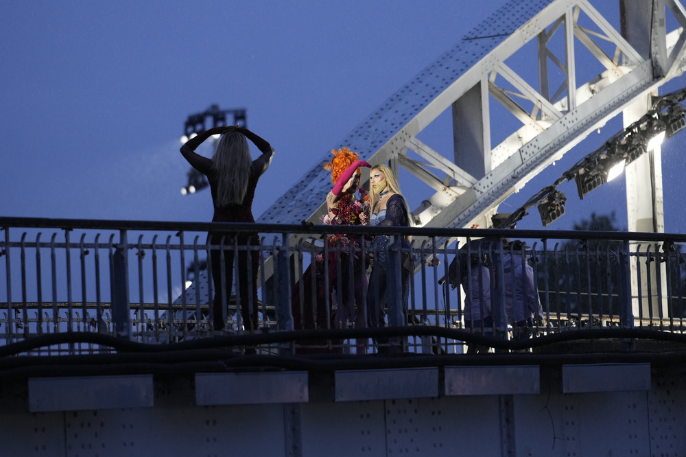 Paris Summer Olympics, 2024. Drag queens on bridge at night, backlit by bridge's arch.