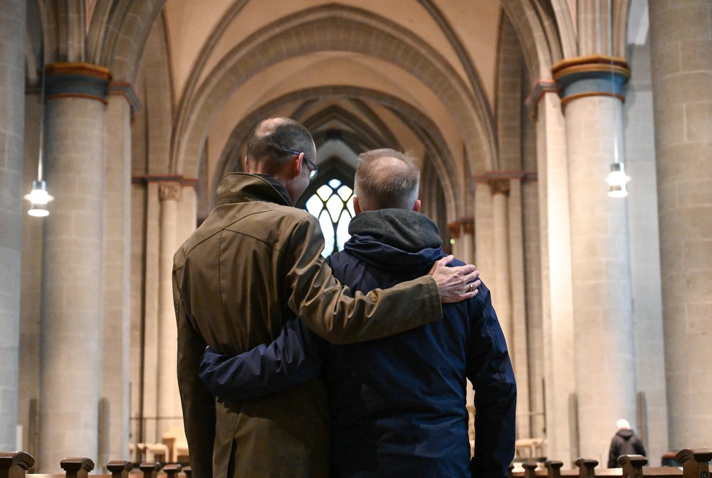 Same sex couple, Essen Cathedral, Germany, Oct. 30, 2021. Two men pictured from behind with arms on each other's shoulder.