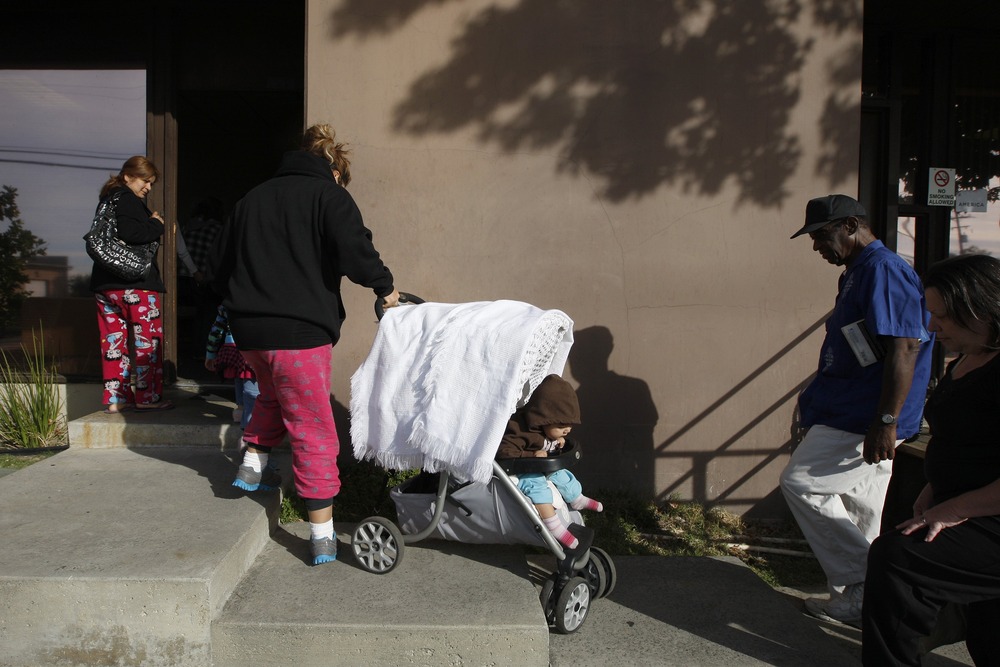 Family enters foodbank, Monrovia, California. Family pulls stroller up cement stairs.