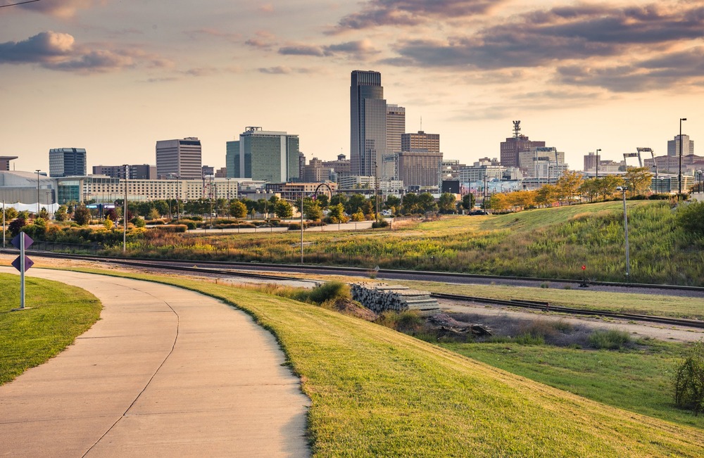 Omaha, Nebraska. Skyline at dusk shown in distance, long green-lined path foregrounded.