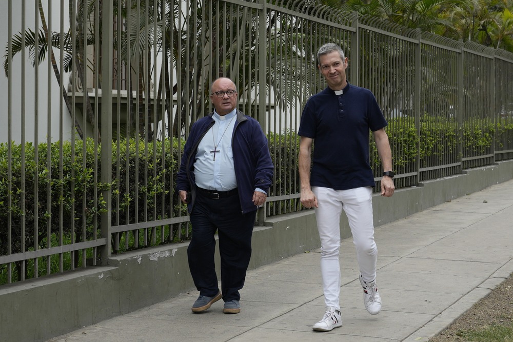 Vatican investigators Monsignor Jordi Bertomeu and Archbishop Charles Scicluna, Lima, Peru, July 25, 2023. Bertomeu and Scicluna walk down sidewalk, wearing street clothes and collars.