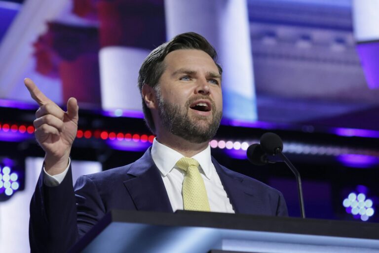 JD Vance, , RNC, 2024. Vance at podium, right hand raised in gesture, screen behind.