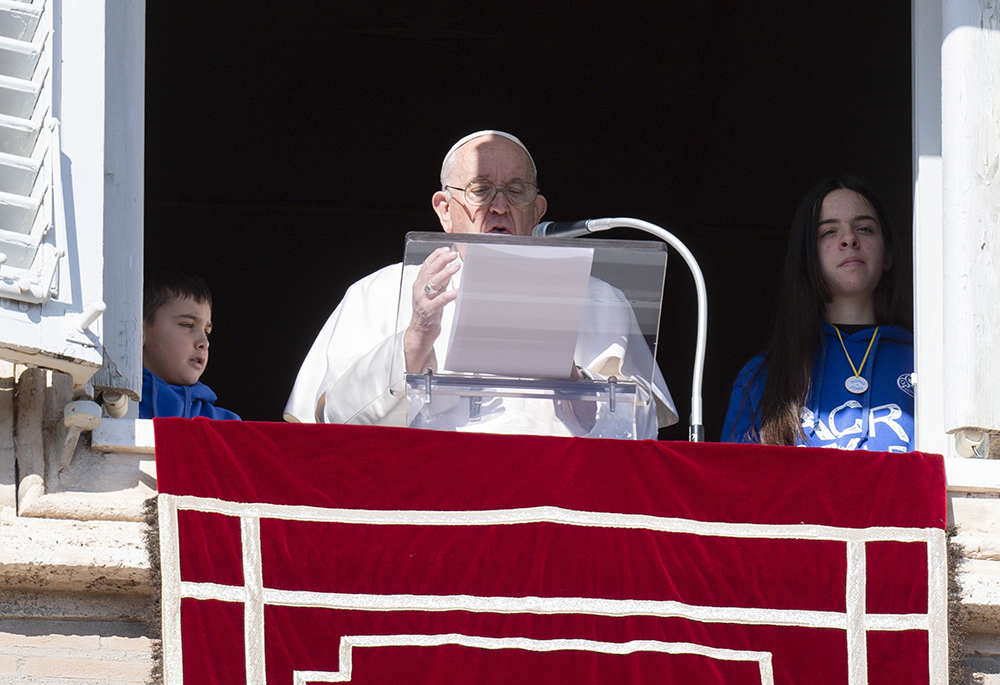 Pope Francis is accompanied by two children as he leads the Angelus from the window of his studio overlooking St. Peter's Square at the Vatican on Jan. 29, 2023. (CNS/Vatican Media)