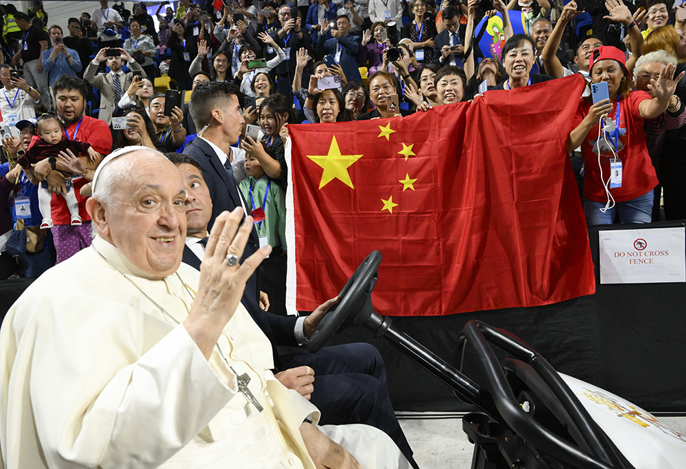Pope Francis waves as people behind him raise a Chinese flag before the pope's Mass in Steppe Arena in Ulaanbaatar, Mongolia, Sept. 3, 2023. At the end of the Mass, the pope sent greetings to China and to Chinese Catholics. (CNS/Vatican Media)