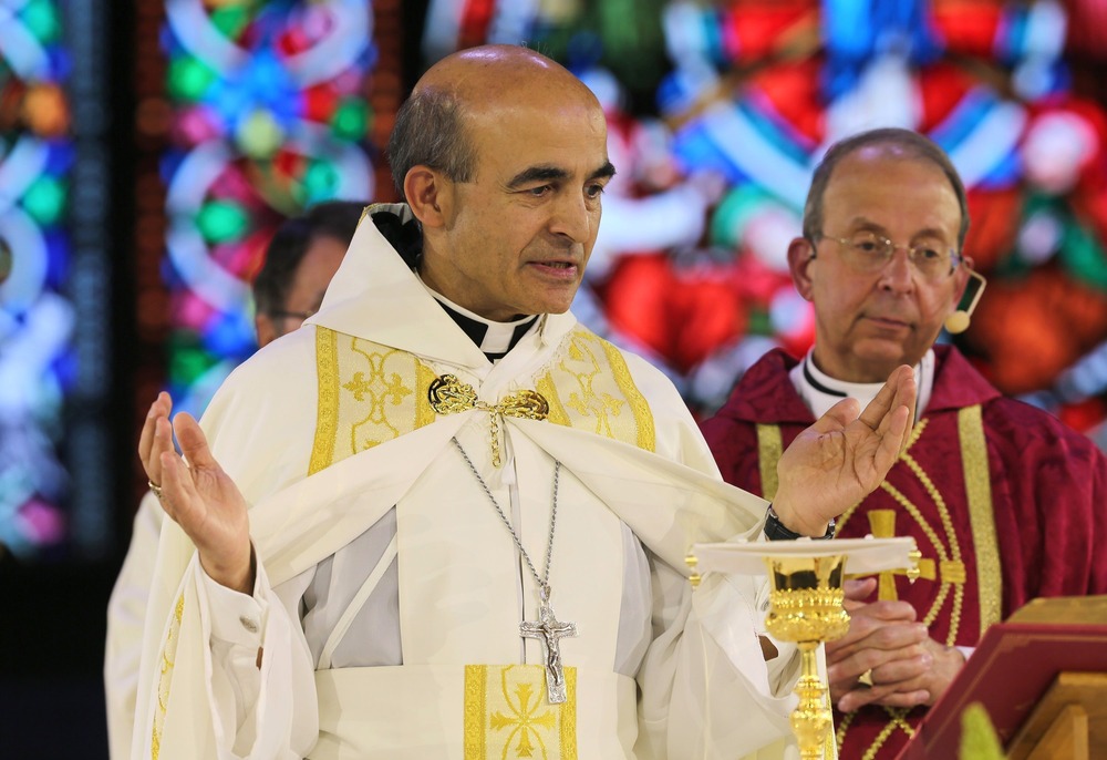 Bishop A. Elias Zaidan of the Maronite Eparchy of our Lady of Lebanon of Los Angeles. Zaidan, vested for Mass, raises hands in prayer at altar.