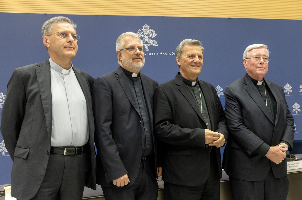 Sept. 16, 2024 press conference for Synod on Synodality, Vatican City. The four men stand in front of a blue and white photo background marked with the synodal insignia.