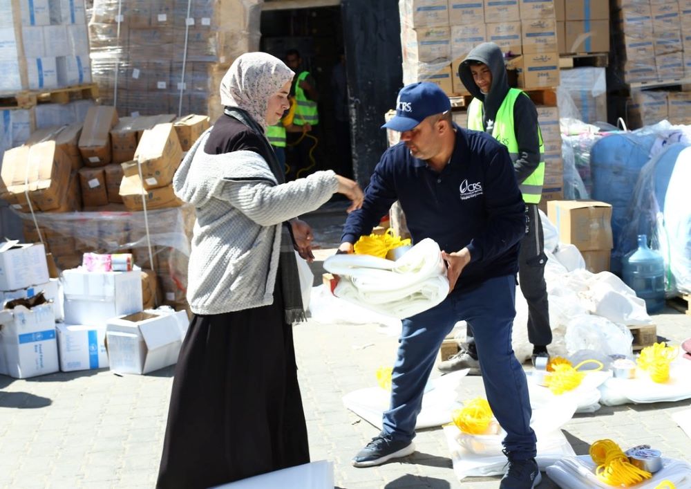 A Catholic Relief Services worker distributes shelter material to a woman in Rafah, in the southern Gaza Strip, March 21. A Catholic Relief Services worker distributes shelter material to a woman in Rafah, in the southern Gaza Strip, March 21.