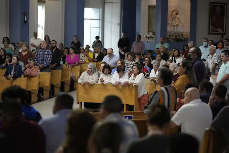 St. Agatha's Catholic Church, Miami, Florida. People in pews praying in a very full church.