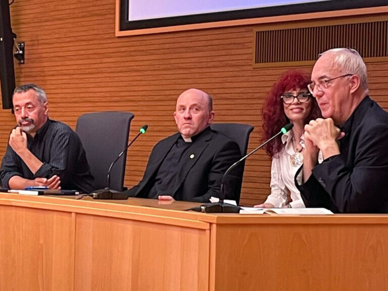 Rome meeting of theologians and physicists, Sept. 6, 2024. The four sit at a wooden desk with microphones.