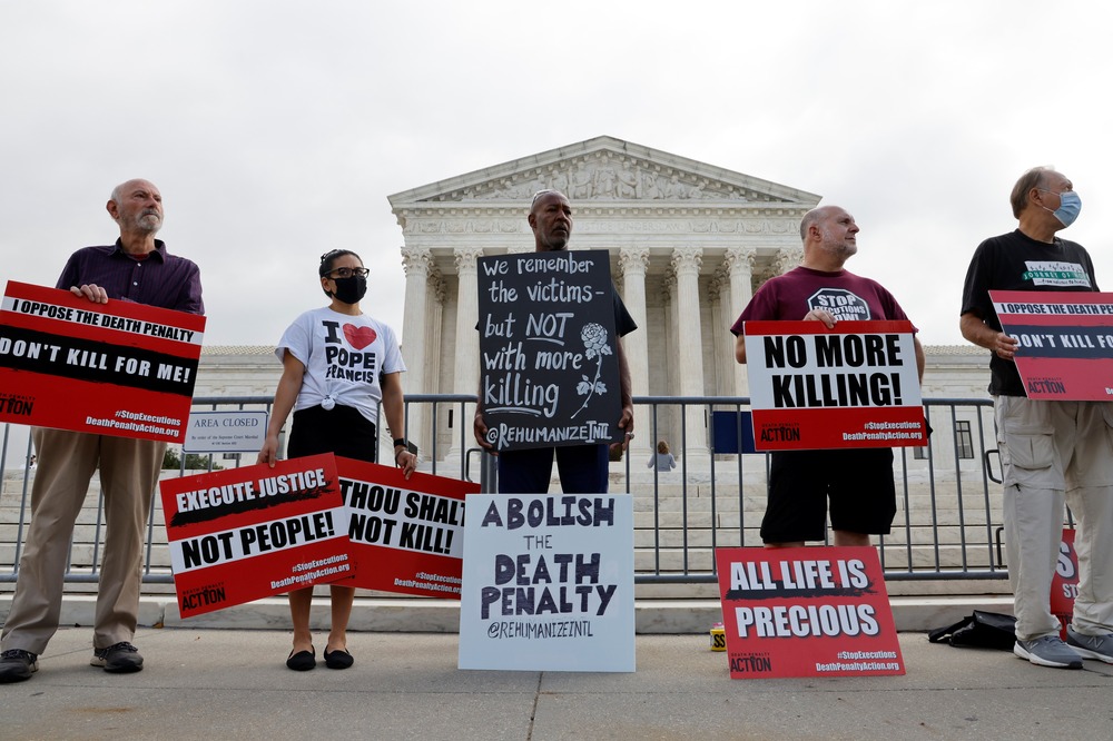 Anti-death penalty demonstrators, Supreme Court building, Washington D.C., Oct. 13, 2021. 5 people stand in front of Supreme Court building holding signs.