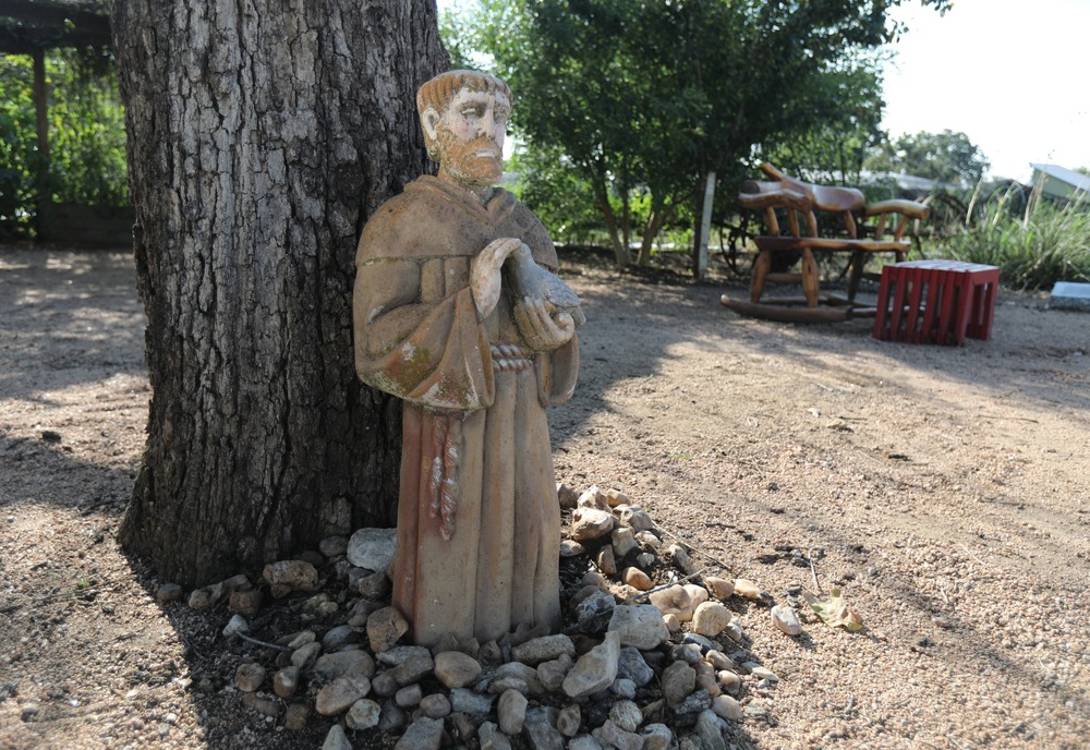 St. Francis statue, Austin, Texas, Sept. 9, 2021. Statue against tree, ringed by stones.