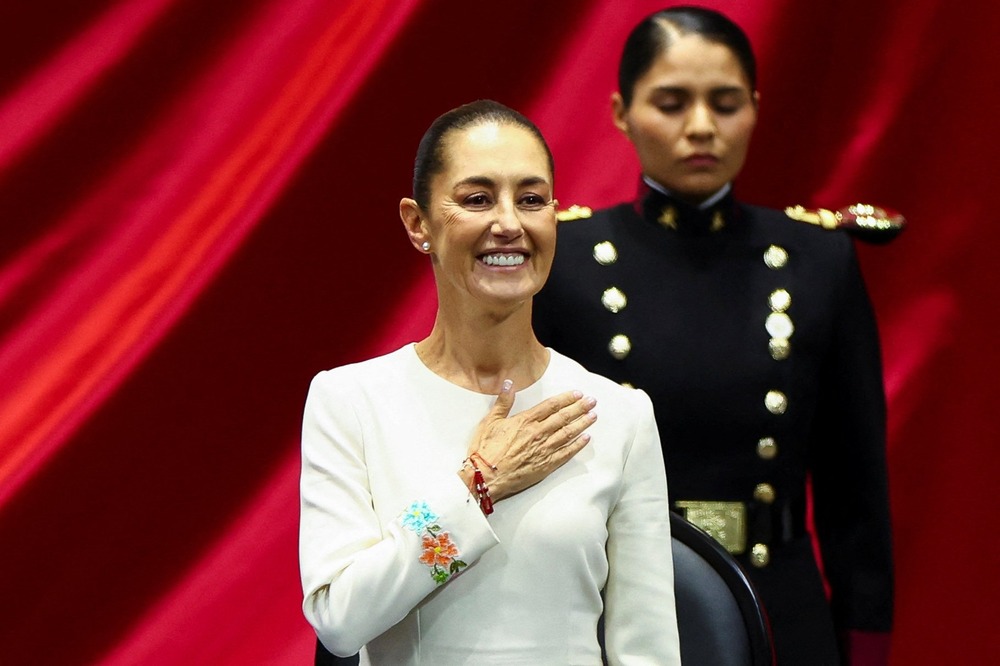 Mexico's President-elect, Claudia Sheinbaum, Mexico City, Oct. 1, 2024. Sheinbaum holds her hand over her heart, in the background is a female soldier.
