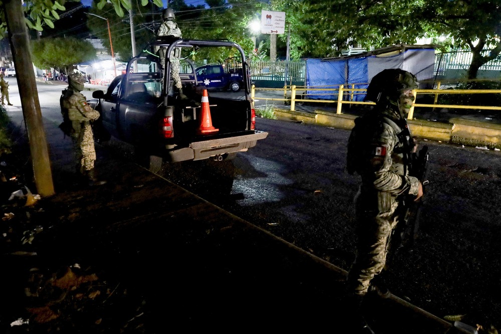 Tapachula, Mexico, OCt. 2, 2024. Two armed soldiers stand in a street at night.