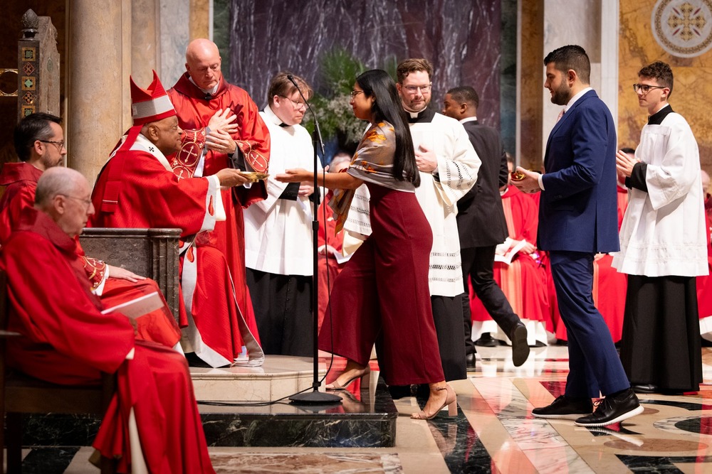 Red Mass, Washington D.C., Oct. 6, 2024. Wilton seated and vested accepts offering from young woman.