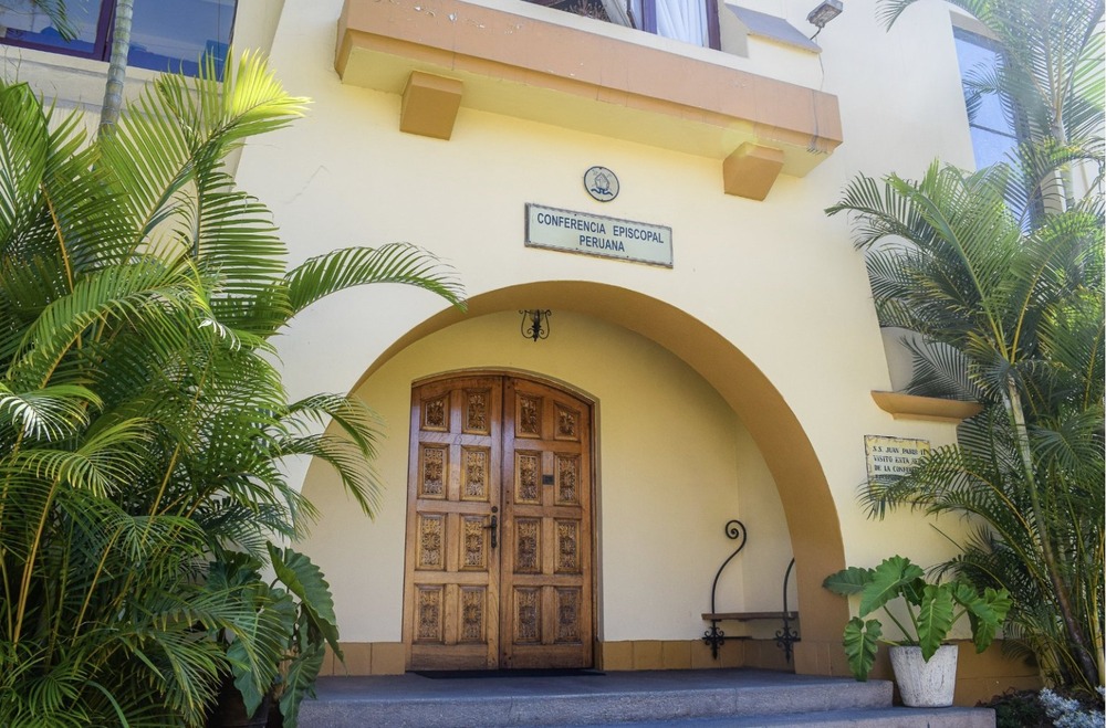 Peruvian Bishops' Conference building. Facade of stucco building, graced by palms.