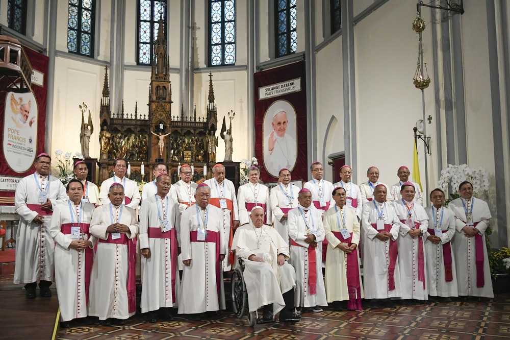 Indonesian bishops and Pope Francis, Cathedral of Our Lady of the Assumption, Jakarta, Indonesia, Sept. 4, 2024. Two rows of cardinals stand in front of altar and behind Pope Francis, seated in wheelchair.