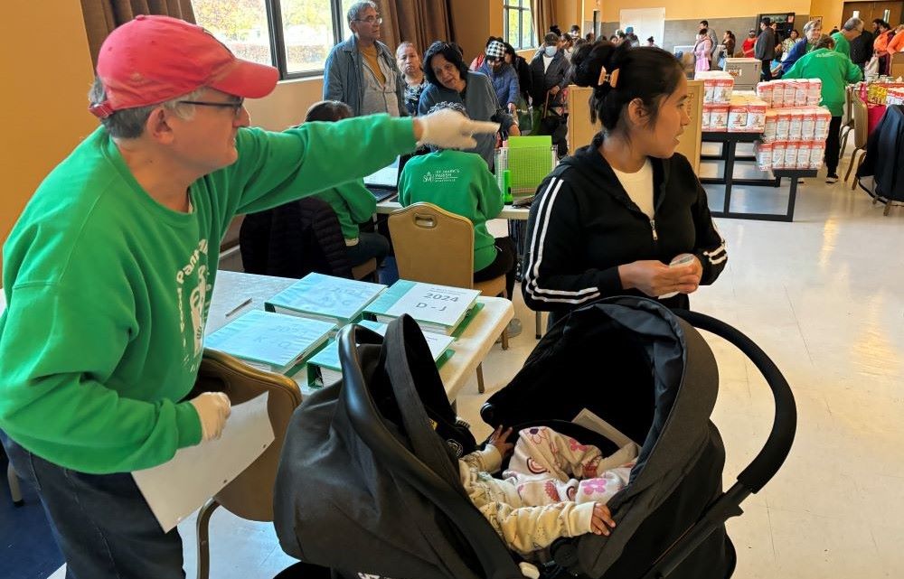 Larry Lojacono directs a pantry client to the food distribution at St. Mark the Evangelist parish. Larry Lojacono directs a pantry client to the food distribution at St. Mark the Evangelist parish.