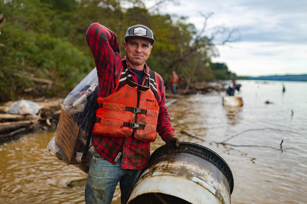 Chad Pregracke, founder of Living Lands and Waters, and 2024 Diocese of Davenport Pacem in Terris award winner. Pregracke stands by river holding debris item.