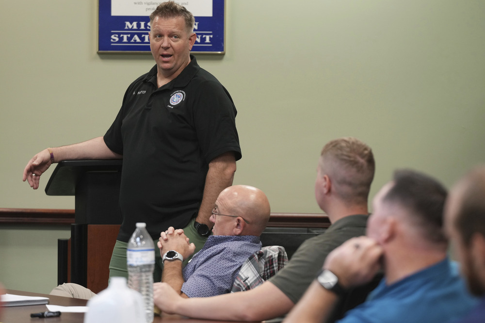 Border Patrol Chaplaincy program manager Spencer Hatch, Dania Beach, Fla., Nov. 20, 2024. Hatch stands in front of lectern, speaking to small, seated group.