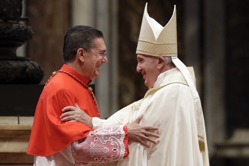Cardinal Miguel Ayuso Guixot and Pope Francis, Vatican City, Oct. 15, 2019. The cardinal embraces the pope, who is vested for Mass in white, wearing mitre.