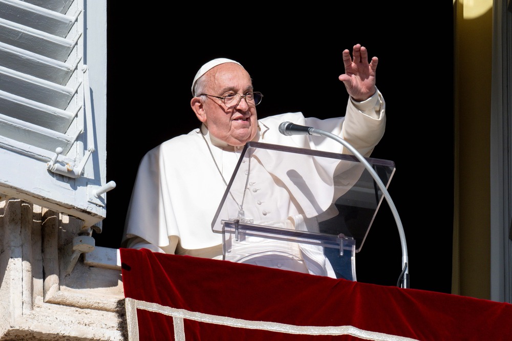 Pope Francis, Angelus, Dec. 2, 2024, Vatican City. The pope stands at lectern in window and waves to people.