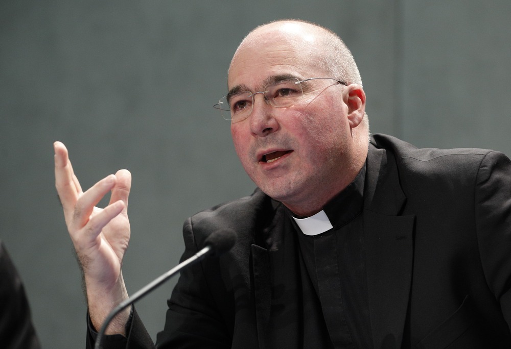 Msgr. Massimo Palombella, 2017. The priest wears black clerics and speaks and gestures into microphone.