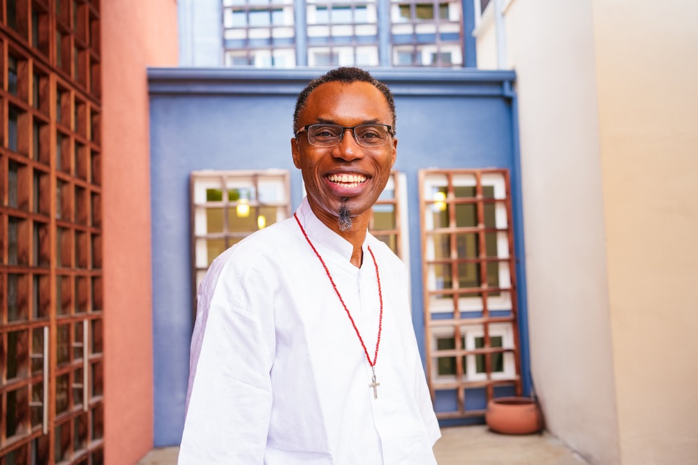 Jesuit Father Agbonkhianmeghe E. Orobator, winner of the Hubert Walter award. The priest wears white clothing and faces camera smiling.