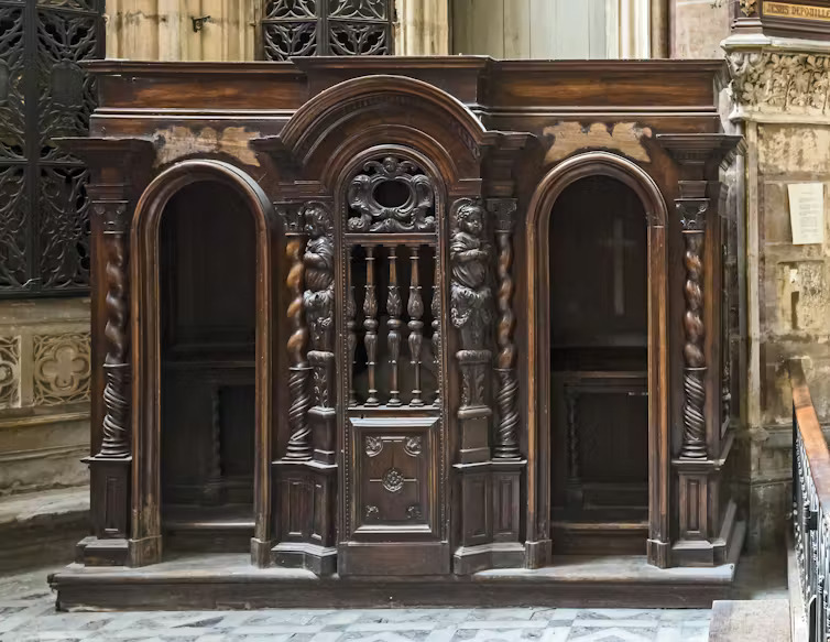 Confessional in St. Stephen's Cathedral, Toulouse. Ornate, carved wooden confessional box.