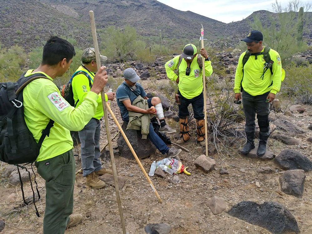 Voluntarios de Águilas del Desierto, una organización de búsqueda y rescate, ayudan a un hombre herido que rescataron en el desierto cuando intentaba cruzar la frontera sur hacia Estados Unidos. (Foto: cortesía Águilas del Desierto)