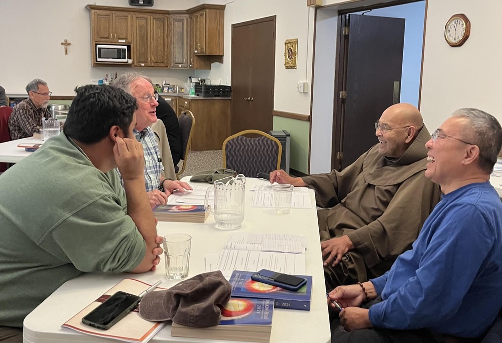 Franciscan synodal meeting, Prior Lake, Minn., October 2024. Four men sit around table laughing and talking.