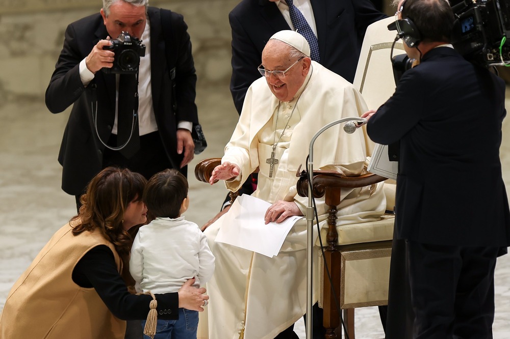 Pope Francis, general audience, Jan. 15, 2025. Francis seated smiles and talks to small child.