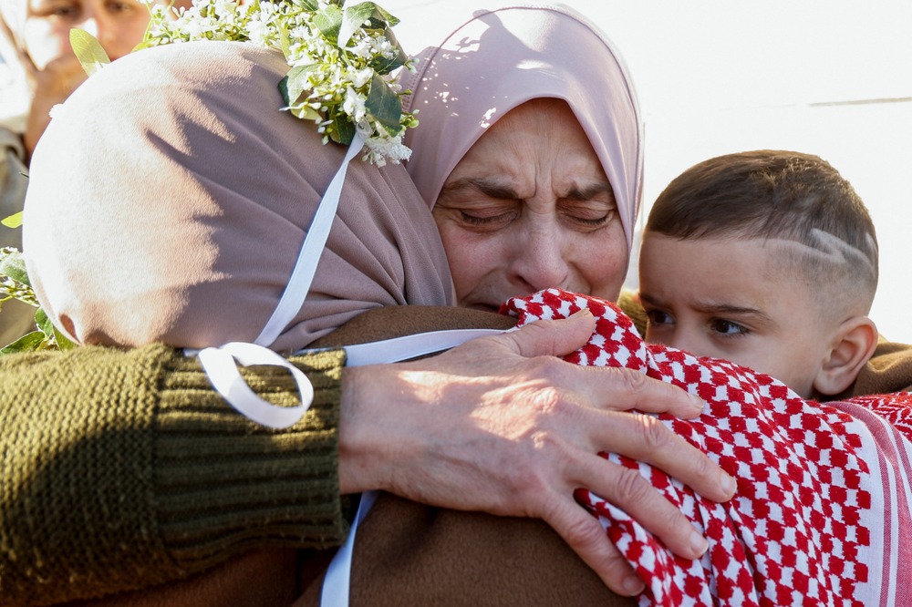 Palestinian prisoner release following 2025 Israel-Hamas ceasefire, Jenin, West Bank, Jan. 20, 2025. Woman's face crinkles with emotion as she embrace other woman and young boy.